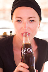 Image showing Woman drinking Coca Cola from brand\'s retro bottle on October the 1th, 2013 in Marrakech, Morocco. Coca Cola is the brand of most famous soft drink in the world.