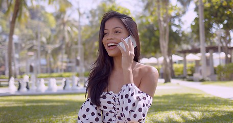 Image showing Lively Asian woman in dress with open shoulder talking on smartphone