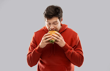 Image showing hungry young man eating hamburger