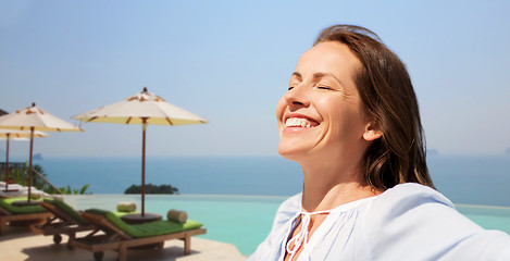 Image showing happy woman enjoying sun over infinity edge pool