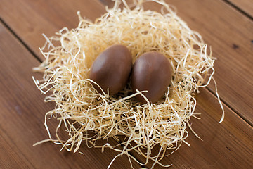 Image showing chocolate eggs in straw nest on wooden table