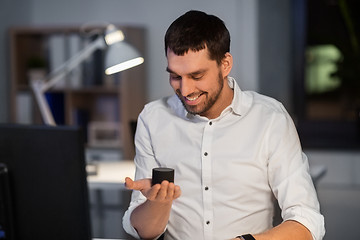 Image showing businessman using smart speaker at night office