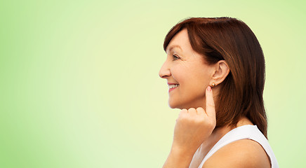 Image showing smiling senior woman pointing to her earring