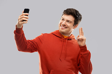 Image showing man in red hoodie taking selfie by smartphone