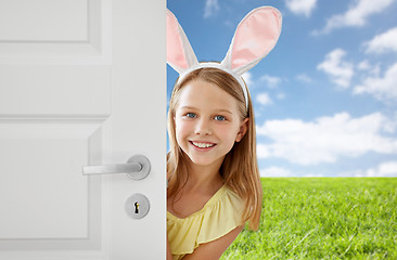 Image showing happy girl with easter bunny ears peeking out door