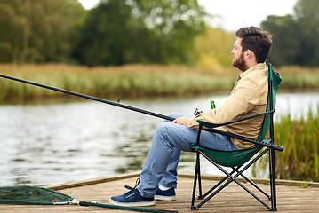 Image showing bearded fisherman with fishing rod at lake