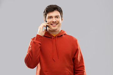 Image showing young man in red hoodie calling on smartphone