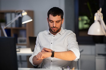 Image showing happy businessman with smart watch at nigh office