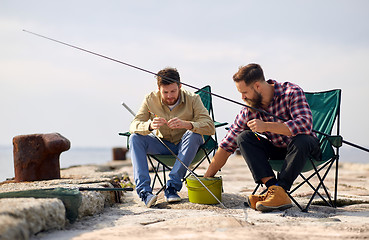 Image showing friends adjusting fishing rods with bait on pier