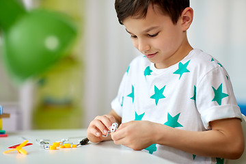 Image showing little boy playing with building kit at home