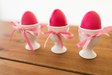 Image showing three pink colored easter eggs in holders on table