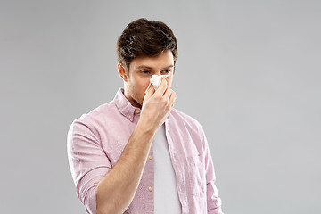 Image showing unhealthy man with paper napkin blowing nose