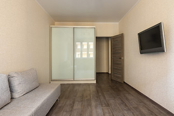 Image showing Interior of a small modest room in a hotel, TV, wardrobe and sofa
