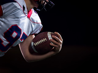 Image showing American football player holding ball while running on field