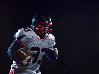 Image showing American football player holding ball while running on field