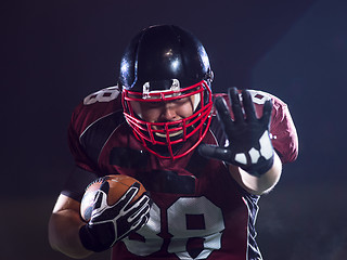 Image showing American football player holding ball while running on field