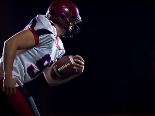 Image showing American football player holding ball while running on field