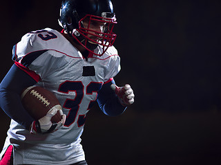 Image showing American football player holding ball while running on field