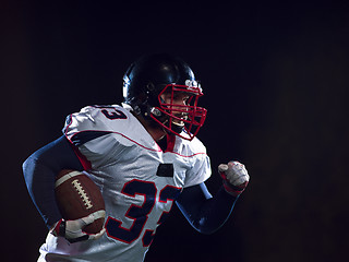 Image showing American football player holding ball while running on field