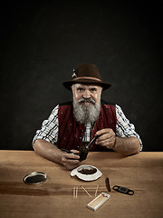 Image showing bearded man clogs the tobacco in pipe