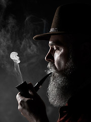 Image showing dramatic portrait of senior smoking tobacco pipe