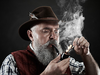 Image showing dramatic portrait of senior smoking tobacco pipe