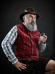 Image showing dramatic portrait of senior smoking tobacco pipe