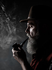 Image showing Black and white dramatic portrait of senior smoking tobacco pipe