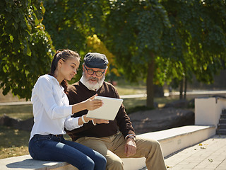 Image showing Portrait of young girl sitting with grandfather at park