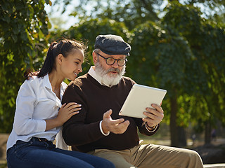 Image showing Portrait of young girl sitting with grandfather at park