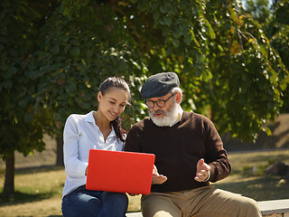 Image showing Portrait of young girl sitting with grandfather at park