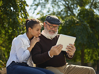 Image showing Portrait of young girl sitting with grandfather at park