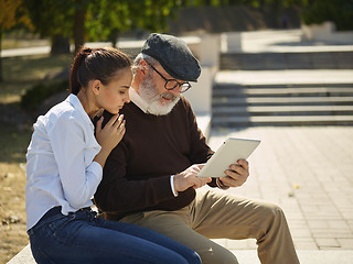 Image showing Portrait of young girl sitting with grandfather at park