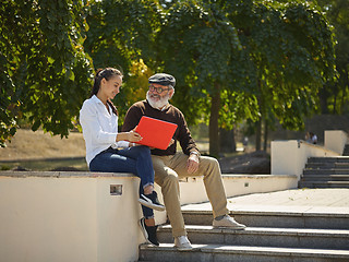 Image showing Portrait of young girl sitting with grandfather at park