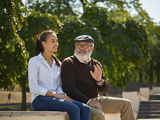 Image showing Portrait of young girl embracing grandfather at park