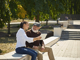 Image showing Portrait of young girl sitting with grandfather at park