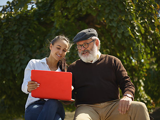 Image showing Portrait of young girl sitting with grandfather at park