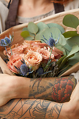 Image showing Close up of fresh tender roses and eryngium in a woman\'s hands with tattoo. Congratulation concept of Mother\'s Day.