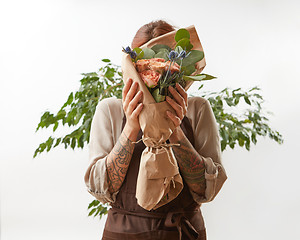 Image showing A fresh gently roses as a bouquet in a female hands on a white background with green leaf, copy space. Post card for Mother\'s Day.