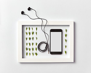 Image showing Frame with organic pine needles pattern, smartphone mock-up and headphones on a light background.