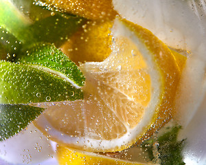 Image showing Macro photo of fresh lime and lemon slices with bubbles in the glass. Summer cold drink