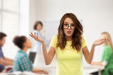 Image showing confused teenage student girl in glasses at school