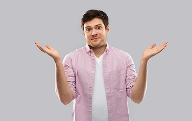 Image showing young man shrugging over grey background