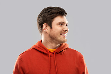 Image showing smiling young man in red hoodie over grey