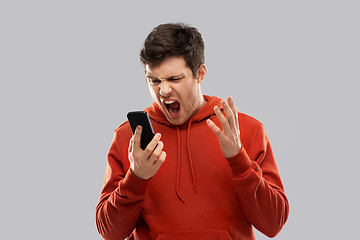 Image showing mad man in red hoodie screaming to smartphone