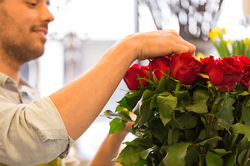 Image showing florist or seller setting red roses at flower shop