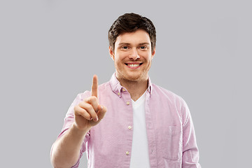 Image showing young man showing one finger over grey background