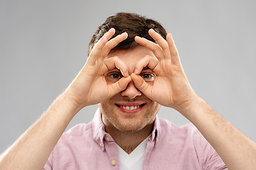 Image showing young man looking through finger glasses