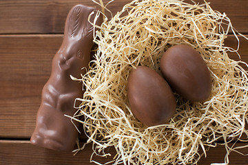 Image showing chocolate bunny and eggs in straw nest on wood