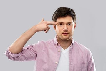 Image showing bored man making headshot by finger gun gesture